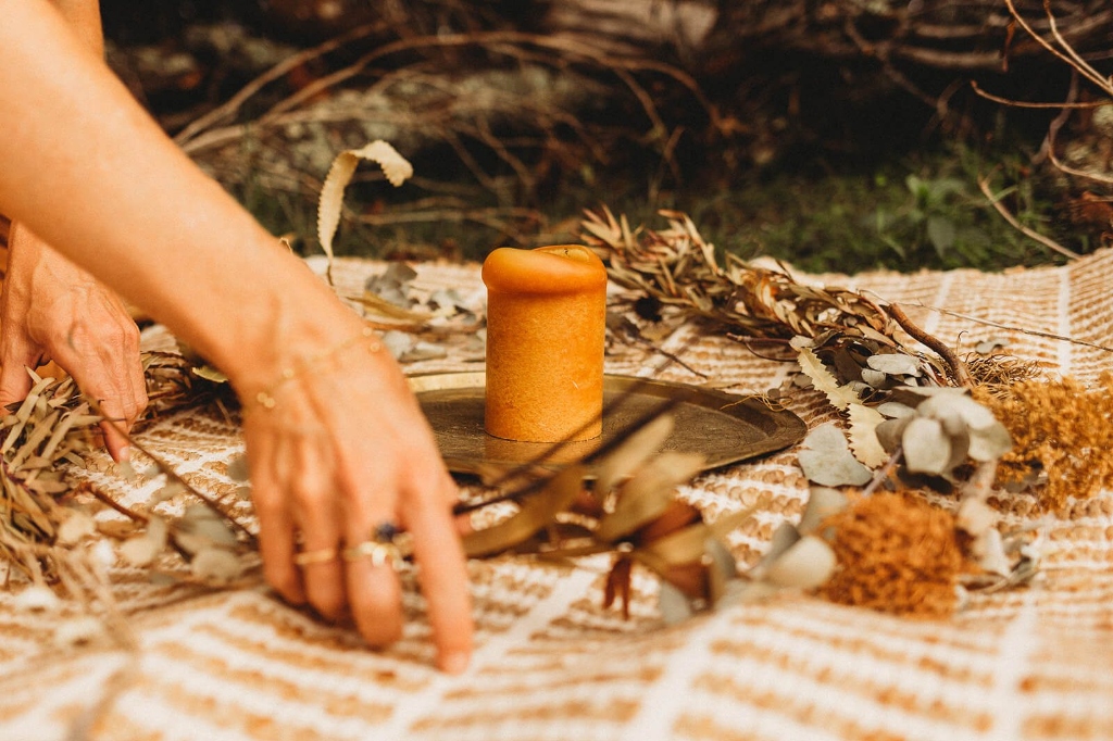 Close-up of a beeswax candle and sacred objects arranged on a woven blanket for a ceremonial sound healing setting by LionHeartCircle