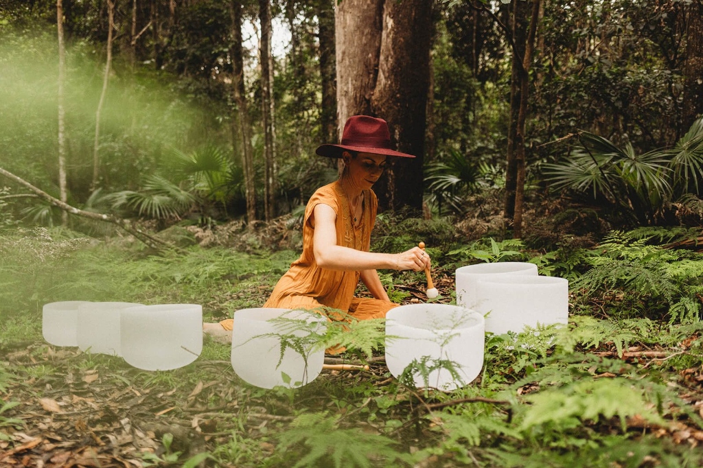 Outdoor sound healing bath surrounded by nature and crystal singing bowls in forest by LionHeartCircle