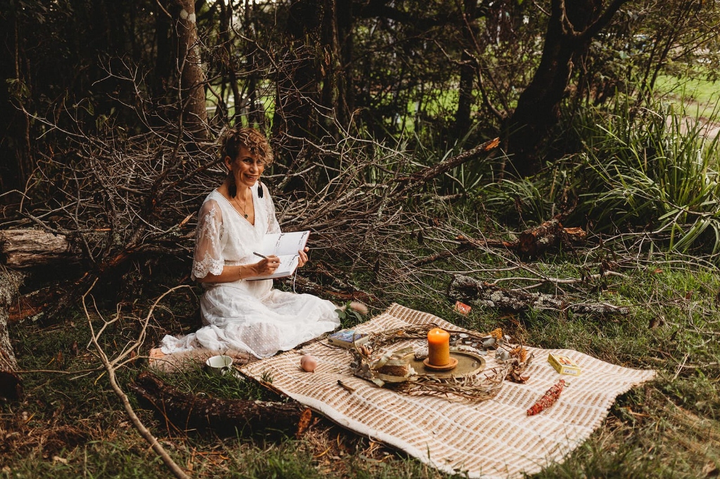Sound healing practitioner sitting on a blanket outdoors, journaling and setting intentions before a sound bath session by LionHeartCircle